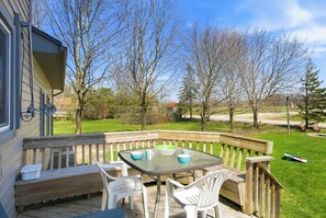 Une terrasse avec une table et des chaises, une clôture en bois et des arbres en arrière-plan.