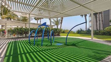 A covered outdoor area with artificial grass, a white pergola, and blue curved structures.