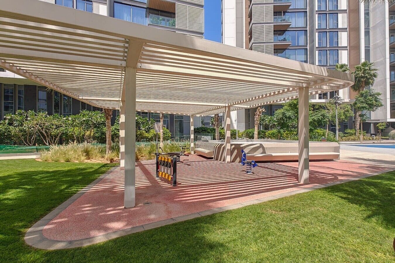 A covered outdoor area with a seating arrangement, a bike rack, and a pool in the background.