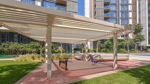 A covered outdoor area with a seating arrangement, a bike rack, and a pool in the background. - Vogue, Bluewater Island steps away from Ain Dubai (Bluewaters Island)