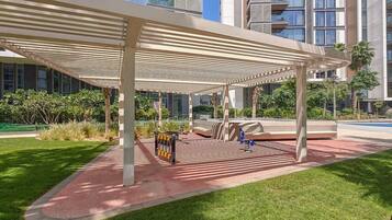 A covered outdoor area with a seating arrangement, a bike rack, and a pool in the background.