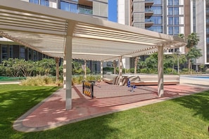 A covered outdoor area with a seating arrangement, a bike rack, and a pool in the background. - Vogue, Bluewater Island steps away from Ain Dubai (Bluewaters Island)