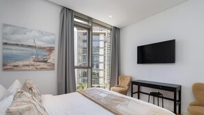 A modern hotel room with a large bed, a TV mounted on the wall, a desk, and a chair. - Vogue, Bluewater Island steps away from Ain Dubai (Bluewaters Island)