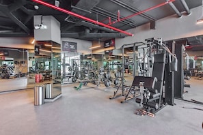 A gym with various exercise equipment, mirrors, and a clean, modern design. - Vogue, Samana Golf Avenue near First Avenue Mall (Dubai Studio City)