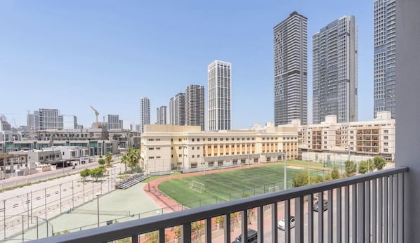 A high-rise building with a sports field in the foreground. - Vogue, JVC Luma22 West near Circle Mall (Jumeirah Village Circle ( JVC ))