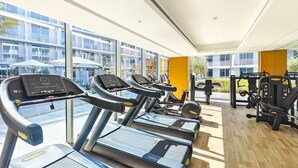 Ein Fitnessstudio mit Laufbändern, Trainingsgeräten und großen Fenstern.