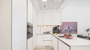 Eine moderne Küche mit weißen Schränken, einem Backofen, einer Kaffeemaschine und einem Spülbecken mit Obstschale.
