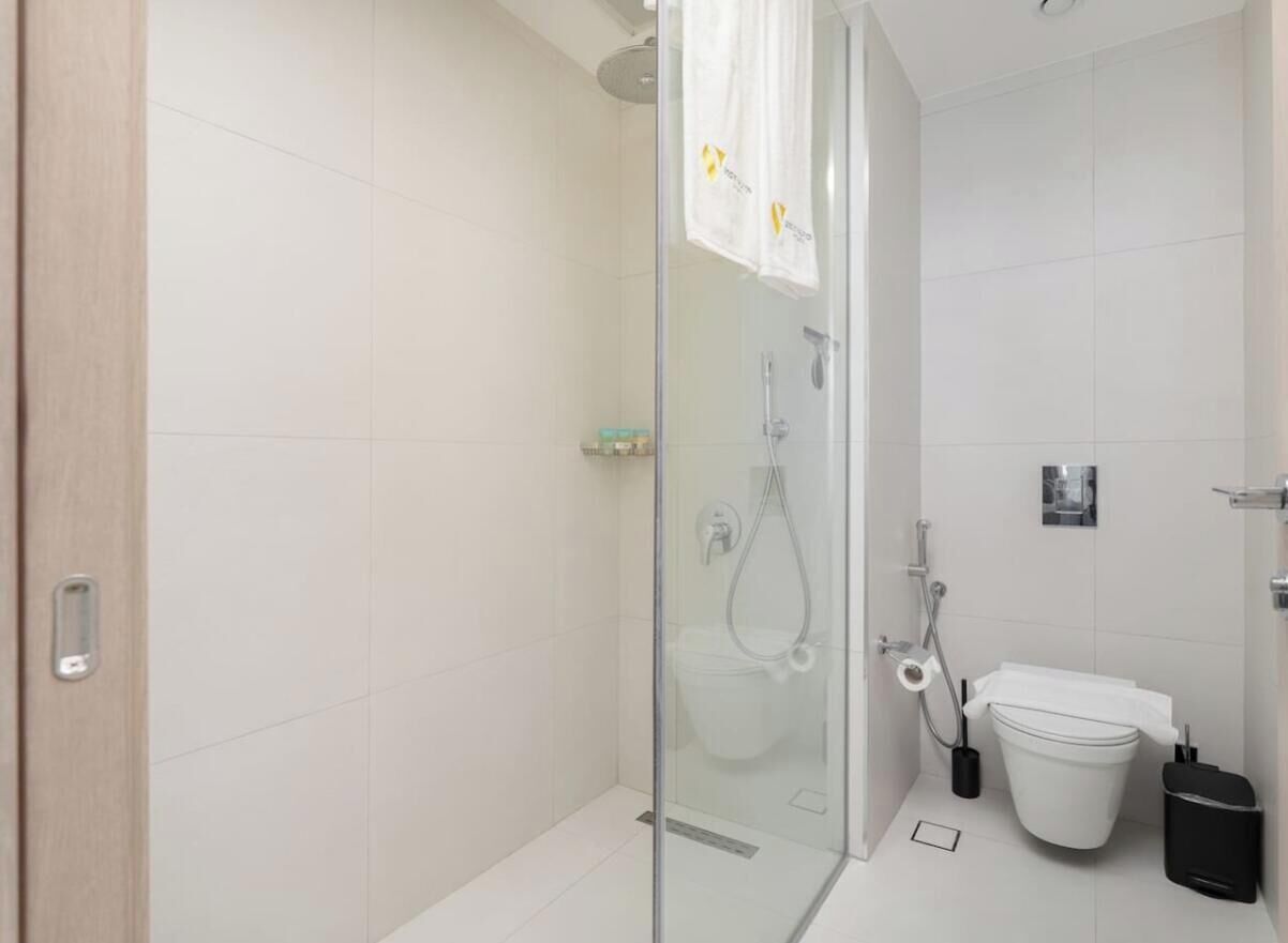 A modern bathroom with a glass shower enclosure, a toilet, and a bidet.