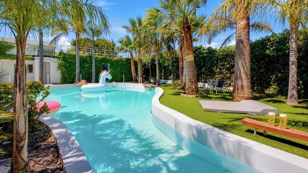 A swimming pool with a slide, surrounded by palm trees and a grassy area. - Villa Tropical |Pool|Jacuzzi|Bar|BBQ|AC|16 Pax (VALENCIA)