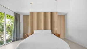 A modern bedroom with a large bed, wooden panel wall, and a view through a large window. - Villa Tropical |Pool|Jacuzzi|Bar|BBQ|AC|16 Pax (VALENCIA)