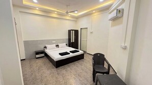 Een slaapkamer met een bed, een stoel, een tafel, een kledingkast en een airconditioning.