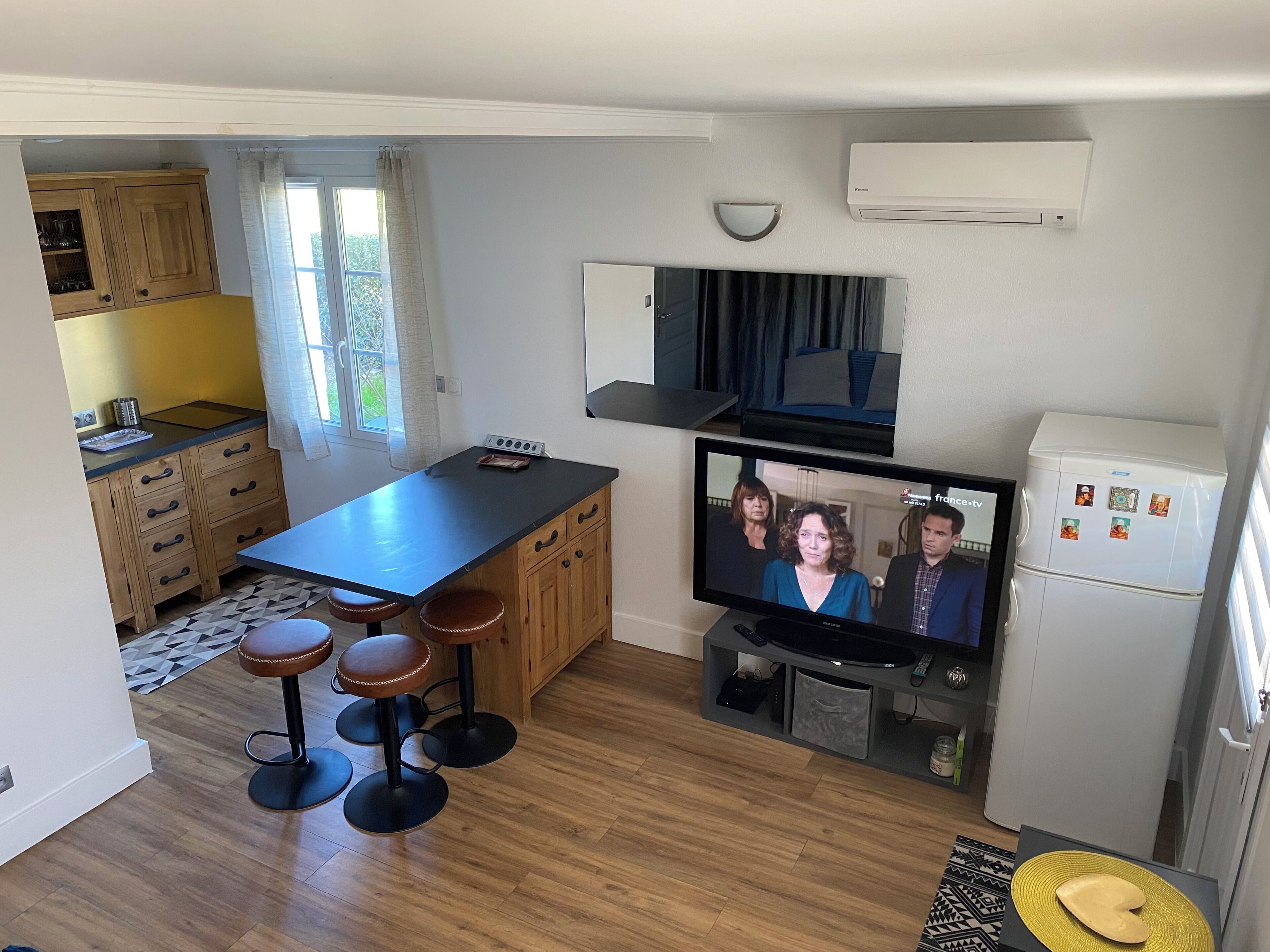 Une cuisine moderne avec des meubles en bois, un plan de travail noir et un téléviseur encastré.