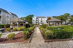 Ein Innenhof mit zwei Lauben, einem Kiesweg und einem Garten mit geschnittenen Büschen.
