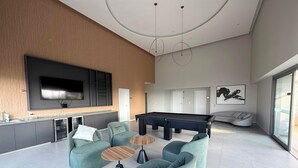 Ein modernes Wohnzimmer mit Billardtisch, Sofas und einem Flachbildfernseher.