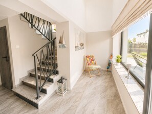 Ein modernes Interieur mit einer Treppe, einem Gemälde, einem Stuhl und einem Fenster mit Blick.