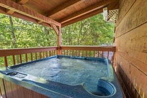 Ein Whirlpool auf einer Holzterrasse mit Blick auf Bäume.
