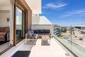Ein Balkon mit einer Couch, einem kleinen Tisch und einem Stuhl.