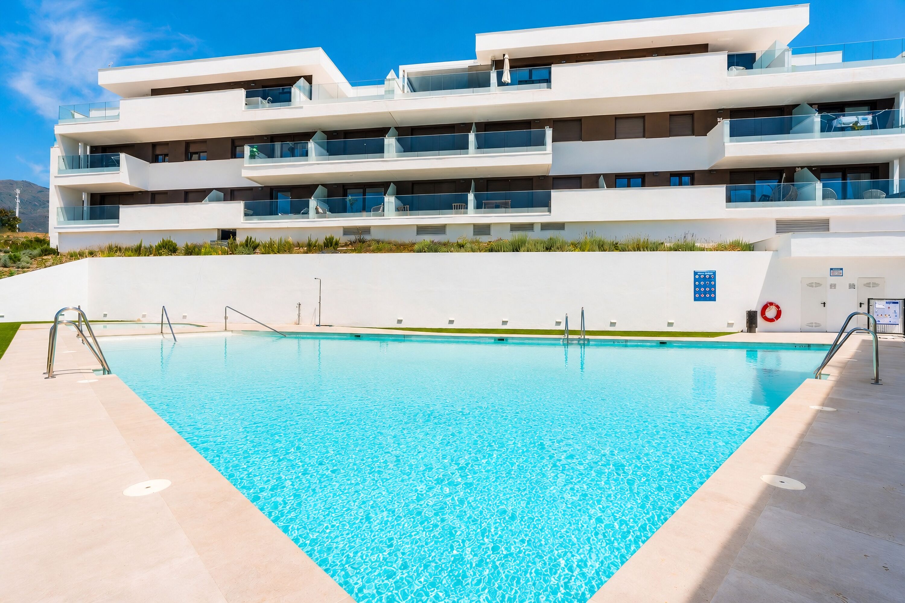Un immeuble moderne à plusieurs étages, avec une piscine située devant.