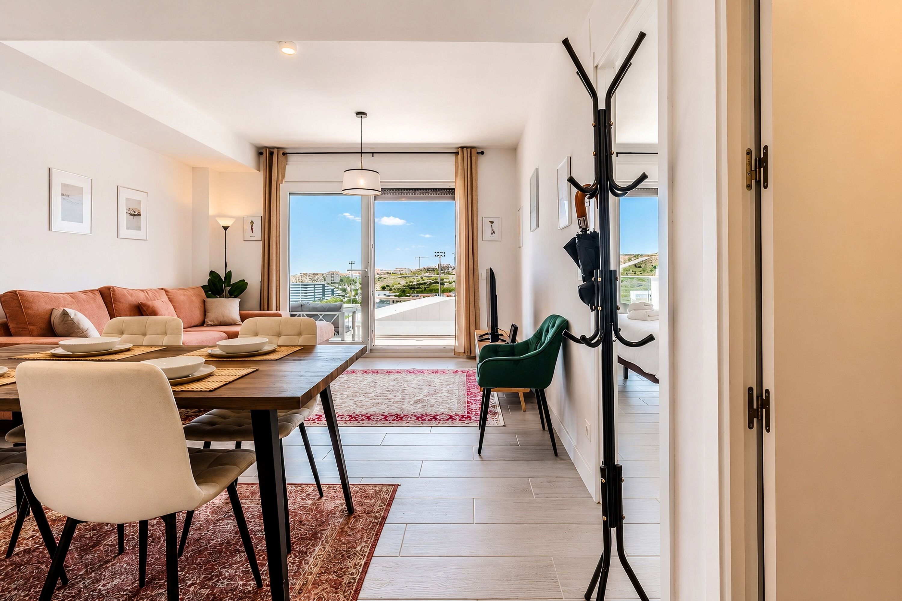 Una sala de estar moderna con sofá, mesa de comedor, sillas y vistas a través de un ventanal.