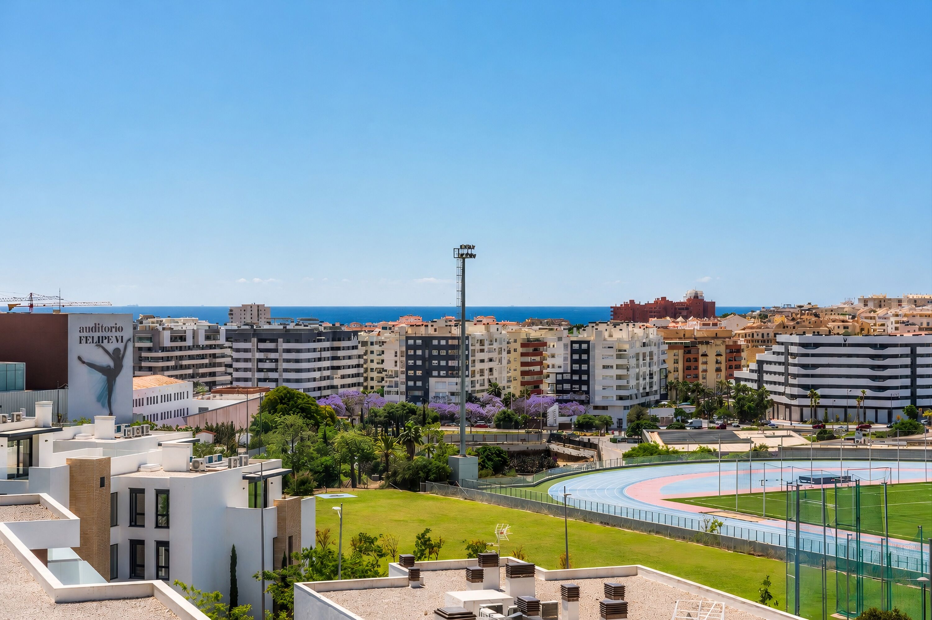 Eine Stadtansicht mit modernen Gebäuden, einem Stadion und blauem Himmel.
