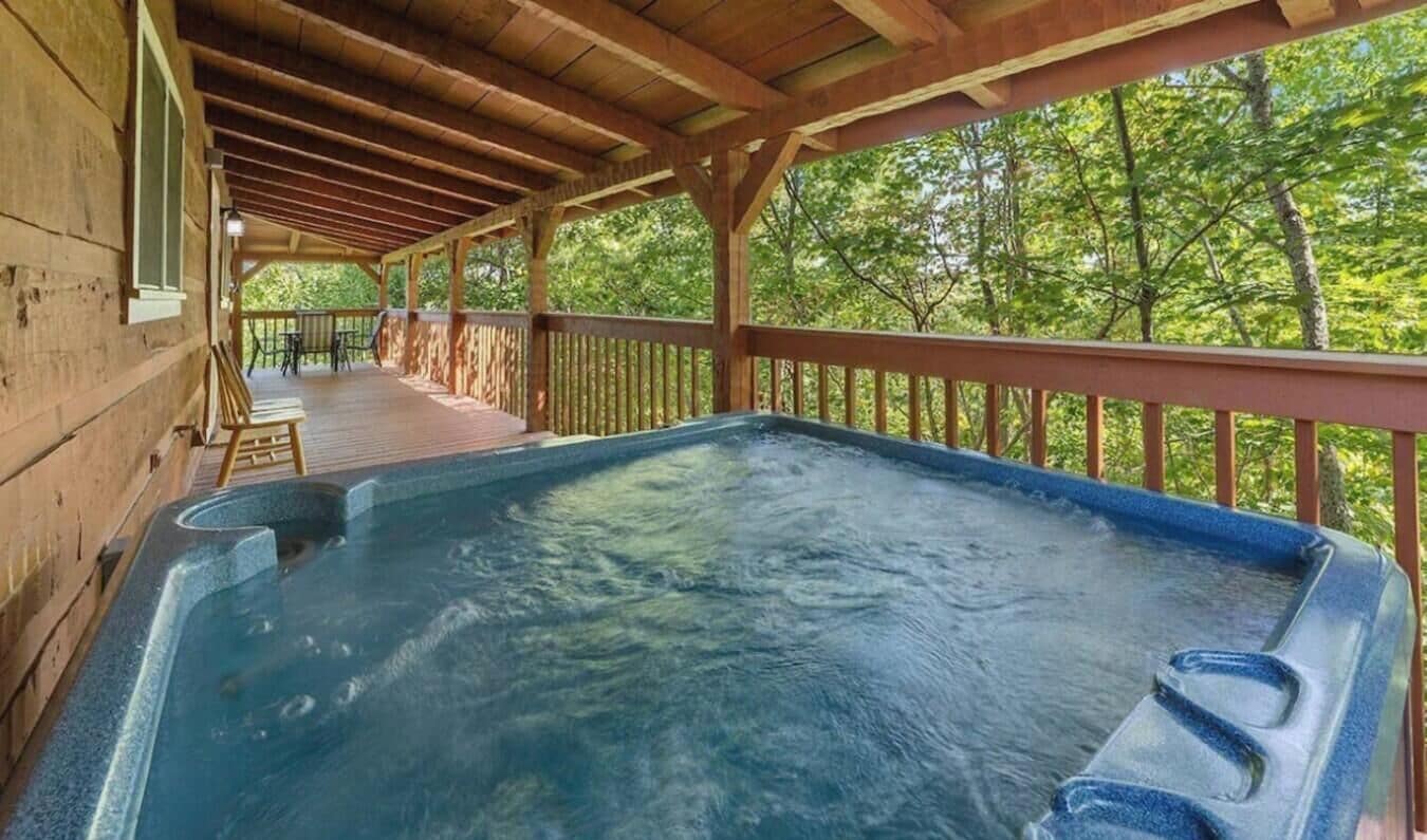 A hot tub under a wooden deck with a view of trees.