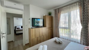 Een hotelkamer met een bed, een televisie, een houten garderobe en een raam met gordijnen.