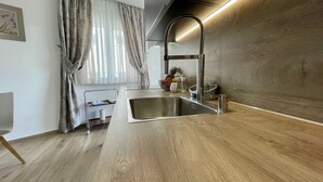 Een moderne keuken met een roestvrijstalen spoelbak, een houten aanrechtblad en een raam met dunne gordijnen.