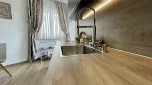 A modern kitchen with a stainless steel sink, wooden countertop, and a window with sheer curtains. - New apartment Doctor Jan with roof terrace, sea and mountain view Ciovo (Okrug Gornji)
