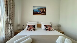 Een hotelkamer met een bed, twee nachtkastjes, een schilderij aan de muur en een raam met gordijnen.