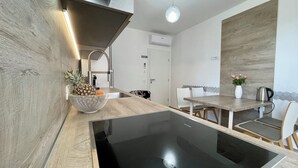 Een moderne keuken met een houten aanrecht, een zwarte inductiekookplaat en een schaal met ananas.