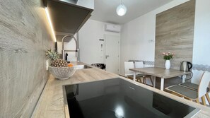 Een moderne keuken met een houten aanrecht, een zwarte inductiekookplaat en een schaal met ananas.