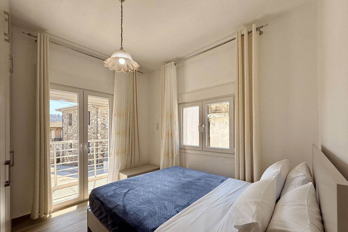 Ein Schlafzimmer mit Bett, einer Hängelampe, einem Fenster und Blick ins Freie.
