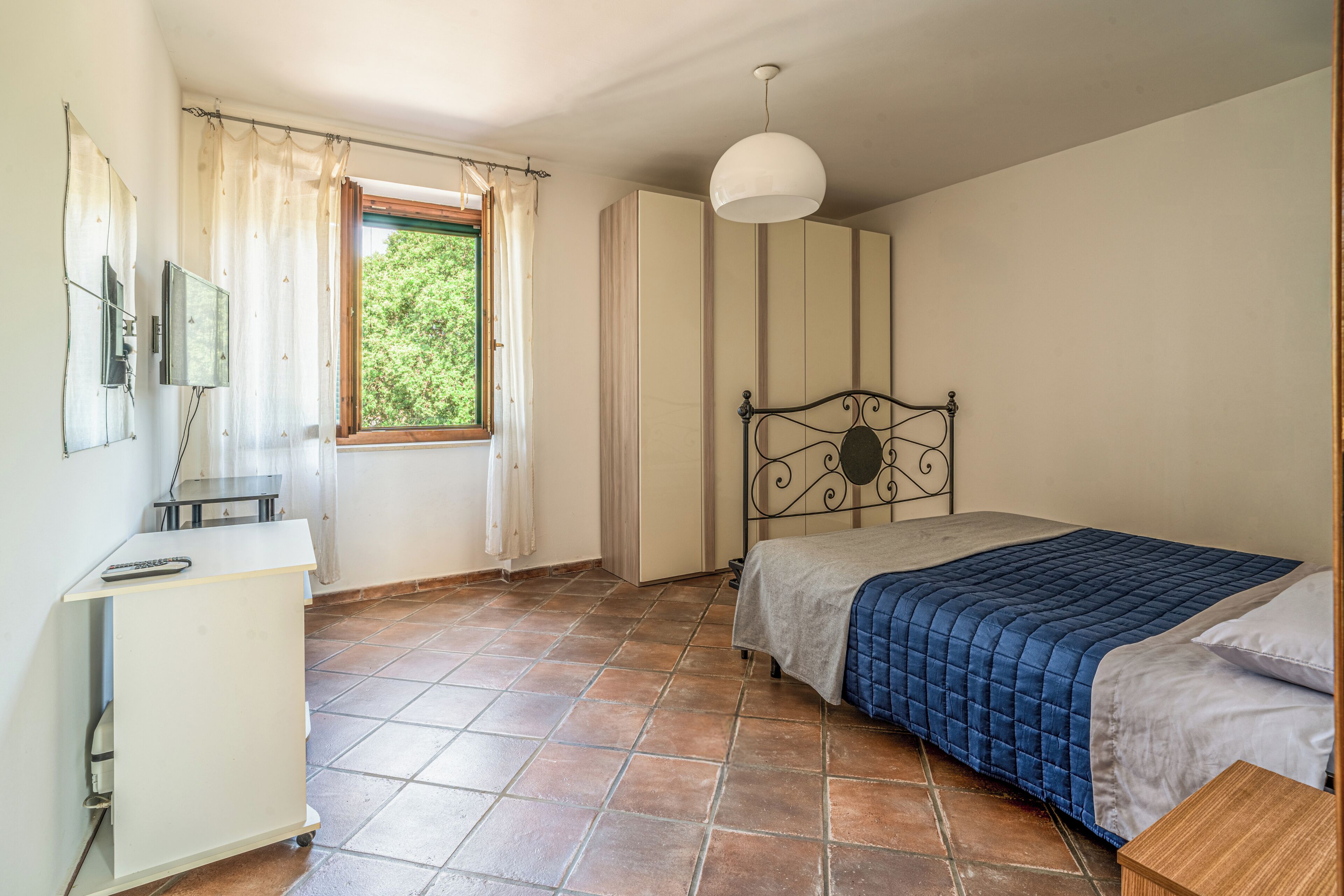 Une chambre à coucher avec un lit, un bureau, une armoire et une fenêtre.