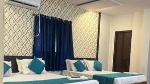 Une chambre d’hôtel avec deux lits, un climatiseur, un ventilateur de plafond et un papier peint à motifs.