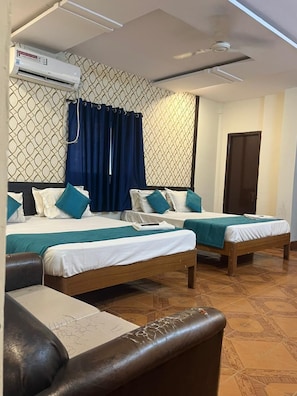 A hotel room with two beds, an air conditioning unit, a ceiling fan, and a patterned wall. - Sree Simran Grand (Hyderabad)