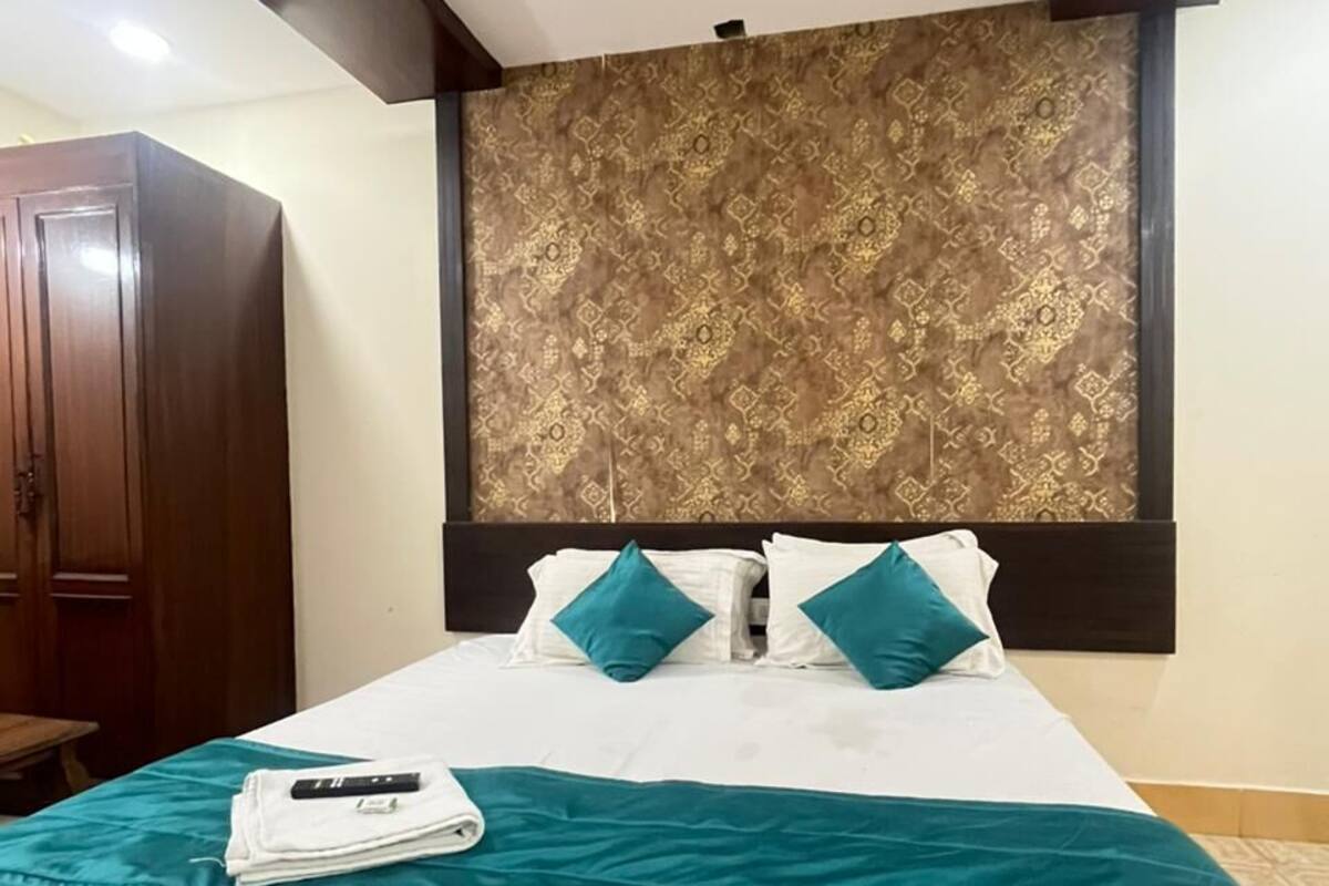 Habitación de hotel con cama, cabecera de diseño estampado, armario y ventilador de techo.