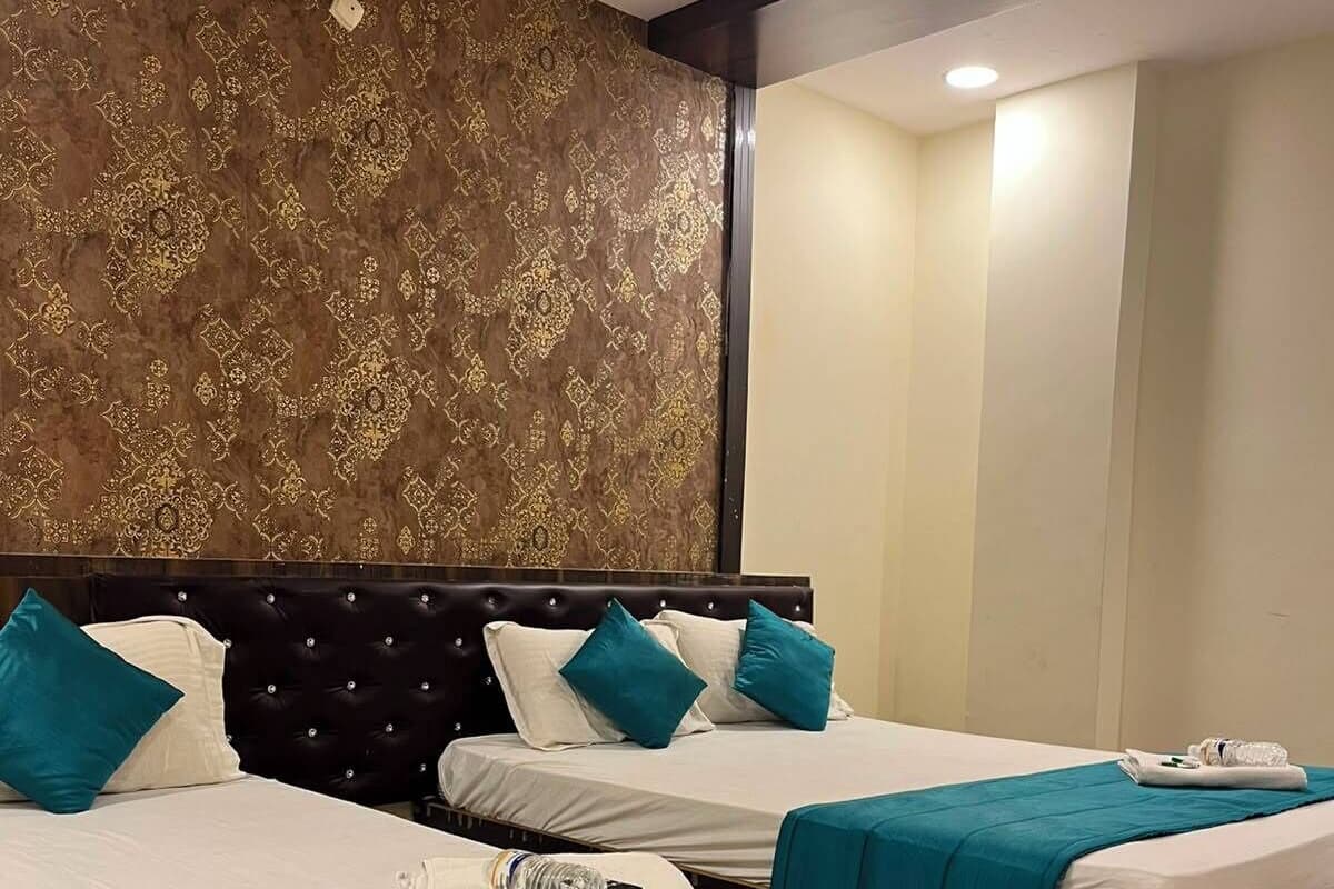 Habitación de hotel con dos camas, cabecera de madera, papel tapiz estampado y suelo de baldosas.