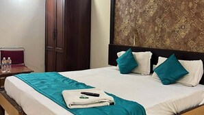 Une chambre d’hôtel équipée d’un lit, d’une armoire, d’une table de chevet et d’un ventilateur de plafond.