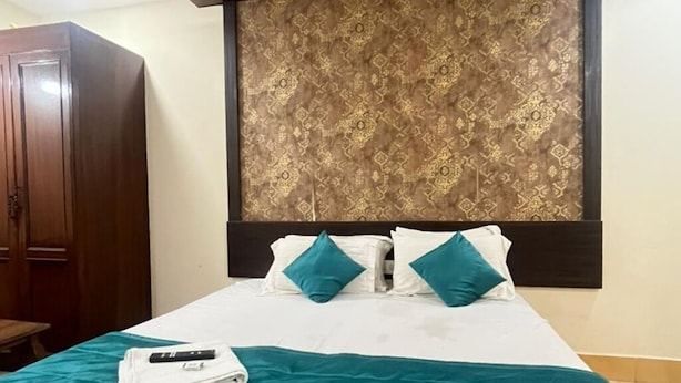 Une chambre d’hôtel avec un lit, une armoire en bois et une tête de lit à motifs.