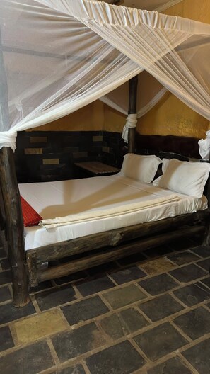 A bed with a wooden frame, white bedding, and a mosquito net.