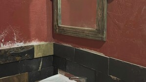 Un bany amb un lavabo blanc, un mirall i una paret vermella.