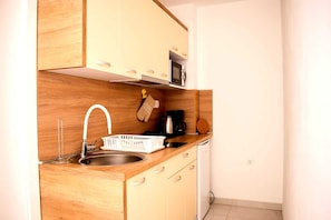 A compact kitchen with wooden cabinets, a stainless steel sink, a microwave, and a coffee maker. - Modern apartment with sea view and balcony in Novi Vinodolski (Novi Vinodolski)