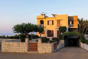 Ein modernes, zweistöckiges Haus mit Steinfassade, einem Balkon und einer Auffahrt zu einer Garage.