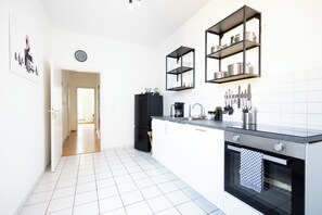 Una cocina moderna con armarios blancos, un refrigerador negro, un horno de acero inoxidable y una encimera negra.