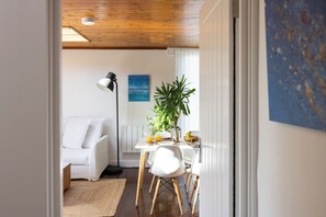 A modern living room with a white sofa, a dining table with chairs, a floor lamp, and a potted plant. - Deck House by the sea (couple or couple + 2 kids) (Emsworth)