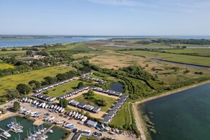 An aerial view of a marina with boats docked, a row of mobile homes, and a large body of water. - Deck House by the sea (couple or couple + 2 kids) (Emsworth)