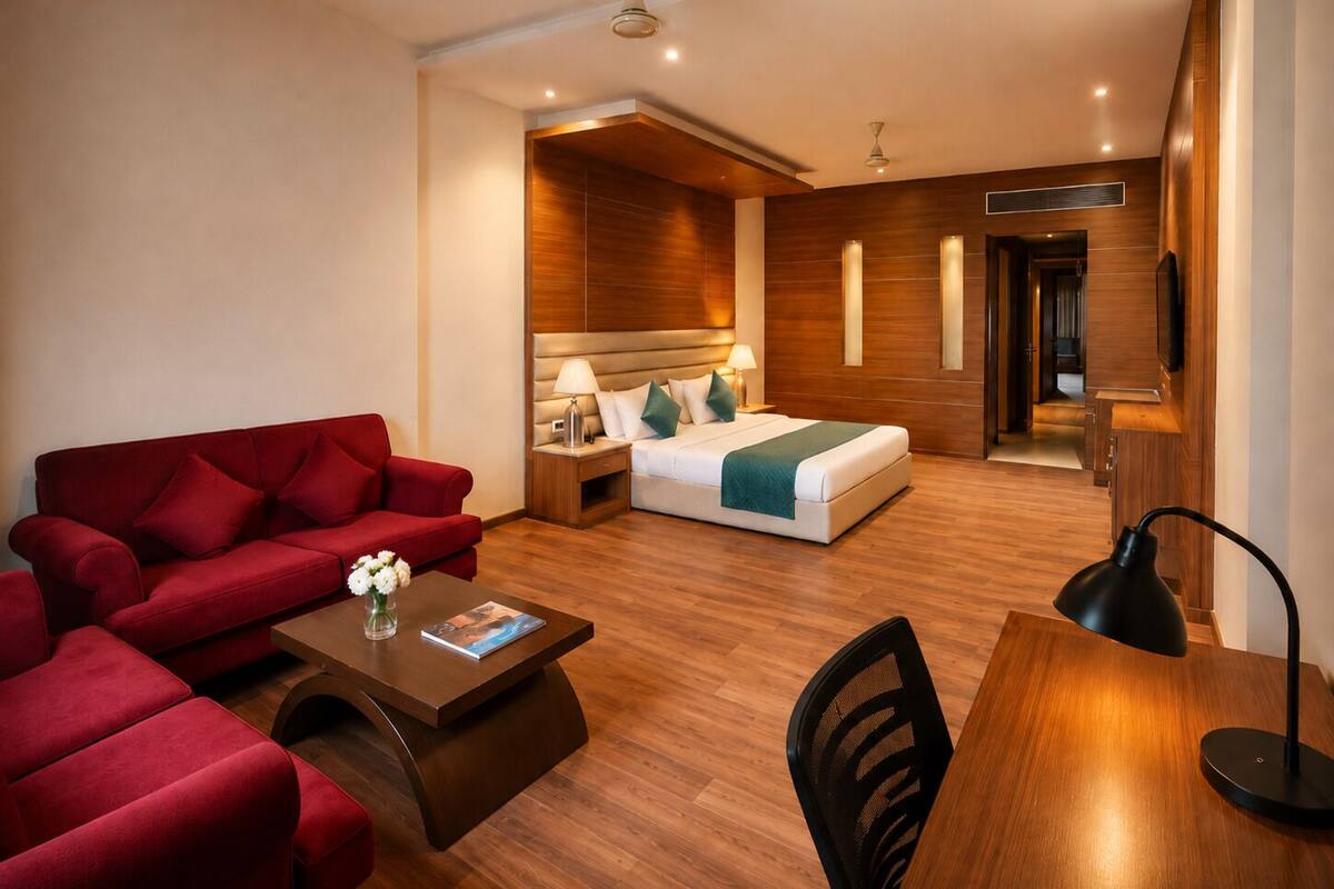 Una habitación de hotel con un sofá rojo, una cama con cabecero de madera, un escritorio, una silla y un televisor.