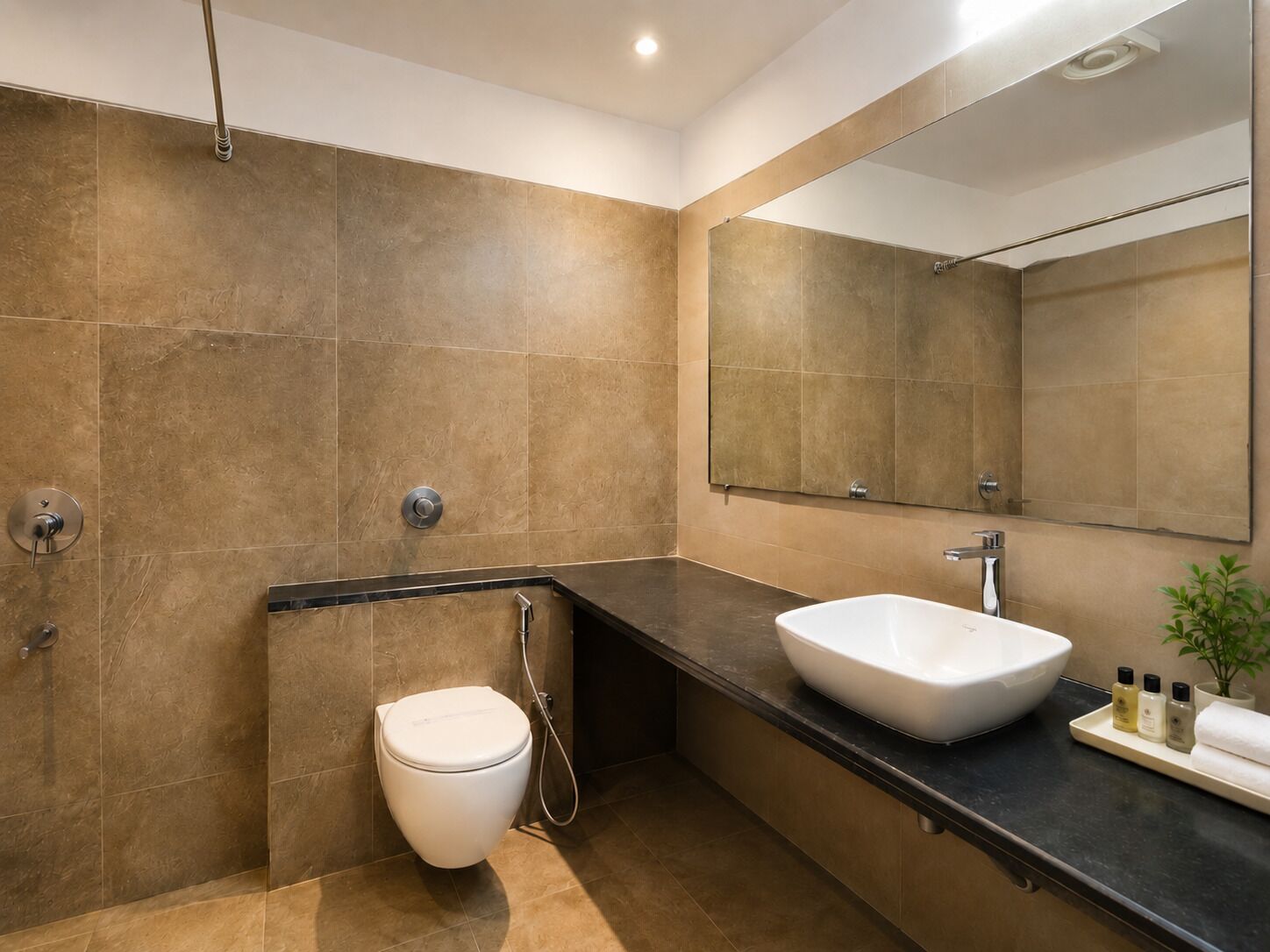 A modern bathroom with a toilet, bidet, sink, and mirror.