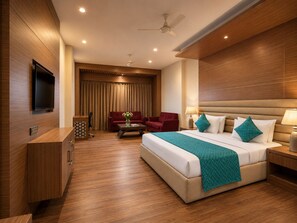 A modern hotel room with a large bed, a desk, a TV, and a ceiling fan.
