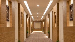 Un pasillo de hotel con alfombra estampada, paneles de madera y luces empotradas.